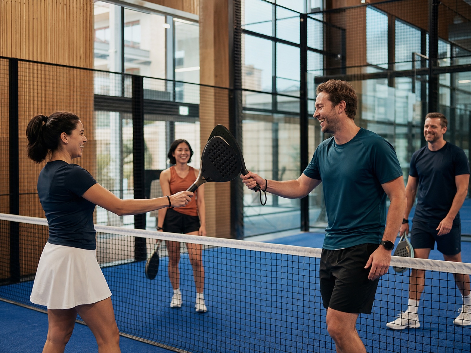 Four neighbours sharing a friendly paddle tap during a casual padel doubles LinkUp